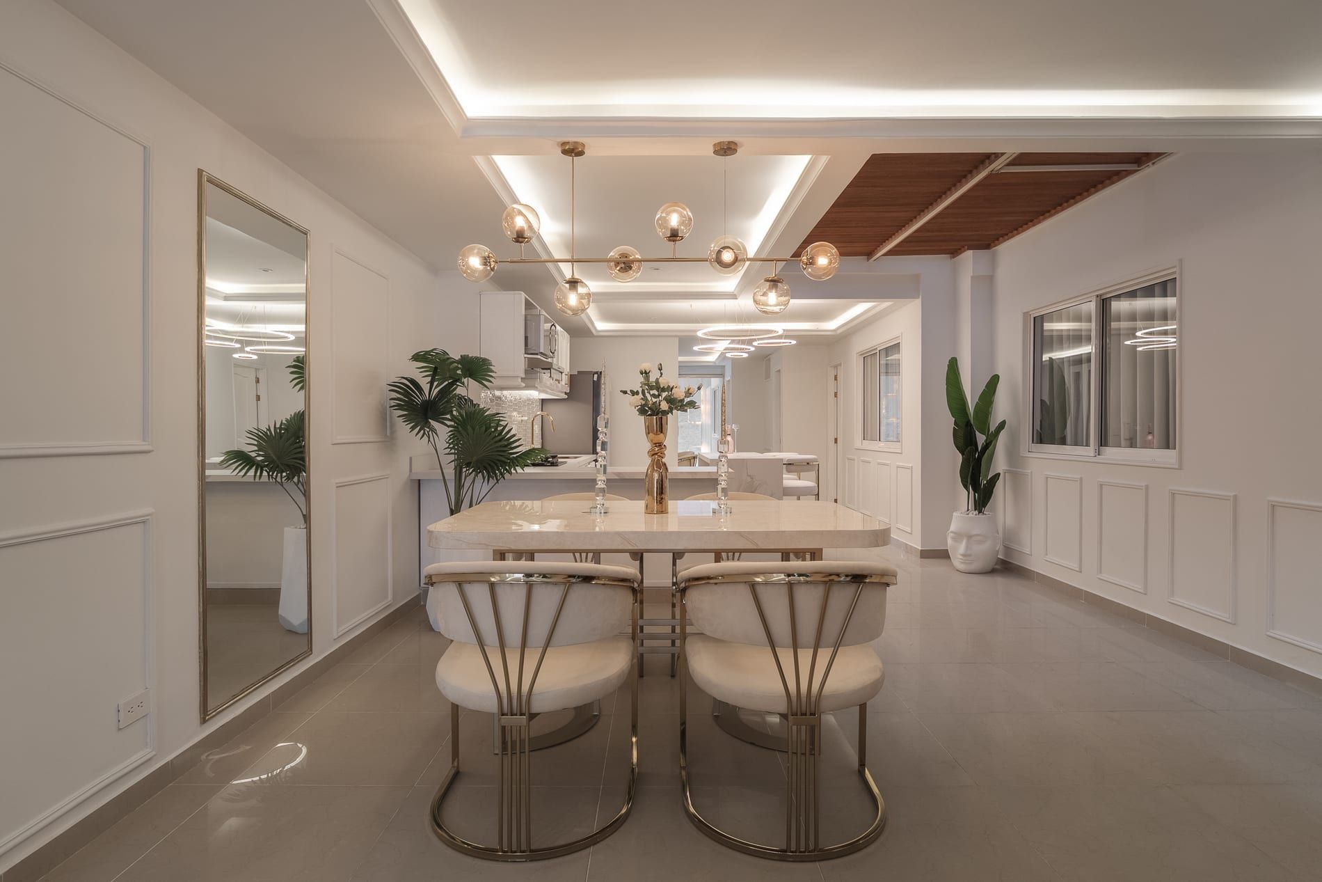 Comedor y sala en blanco con acentos dorados, molduras y luz indirecta