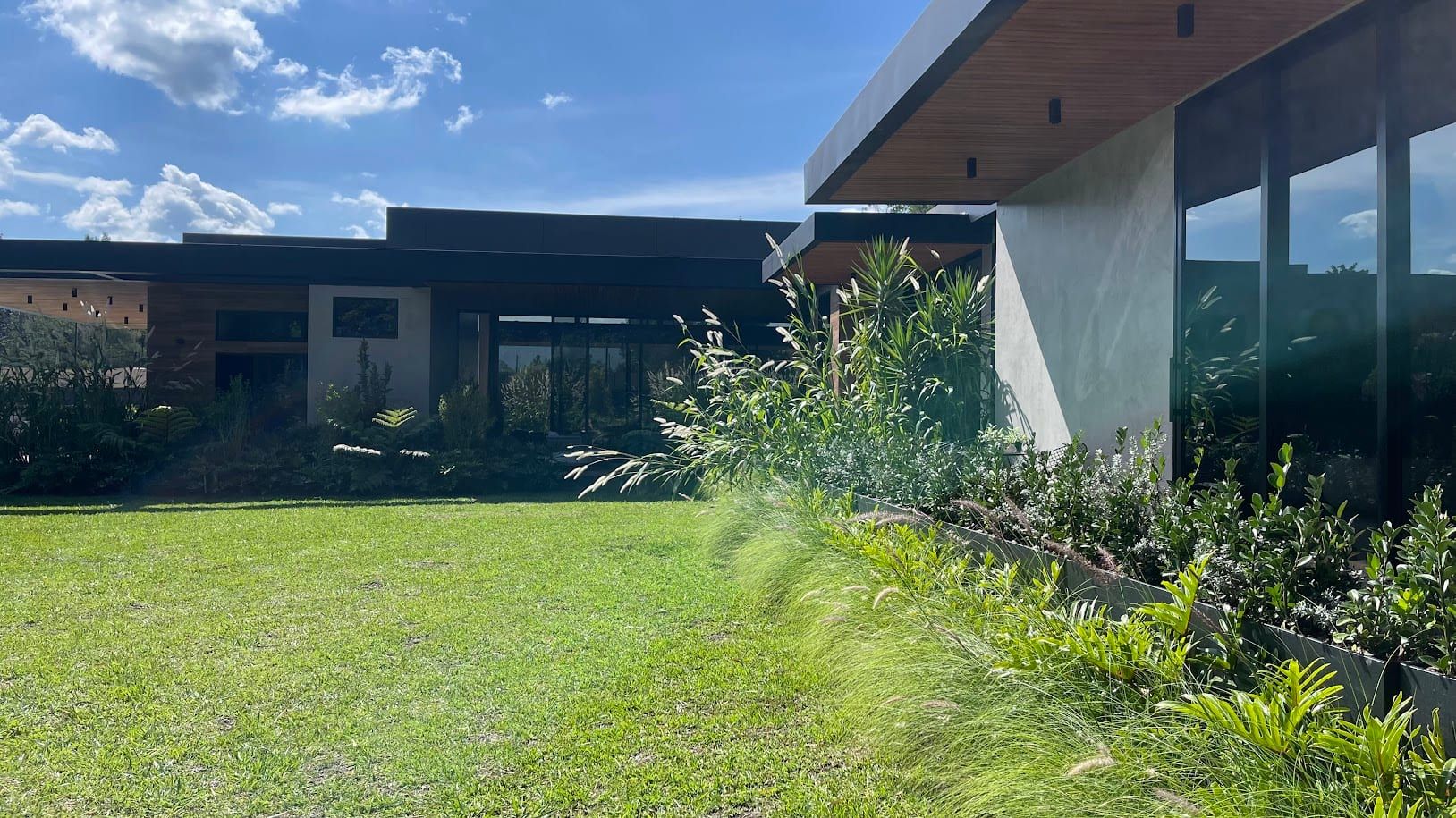 Fachada de la casa vista desde el césped, con plantas en primer plano