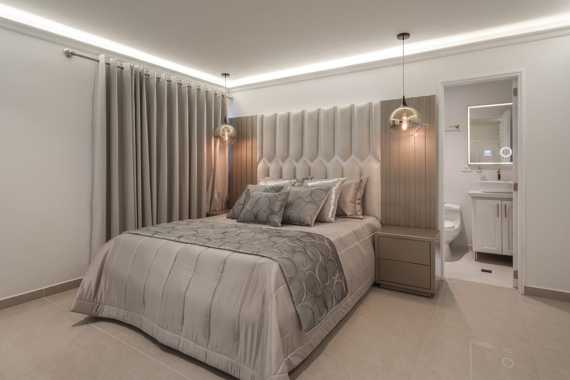 Alcoba principal con cabecero capitoné, cortinas y lámpara colgante