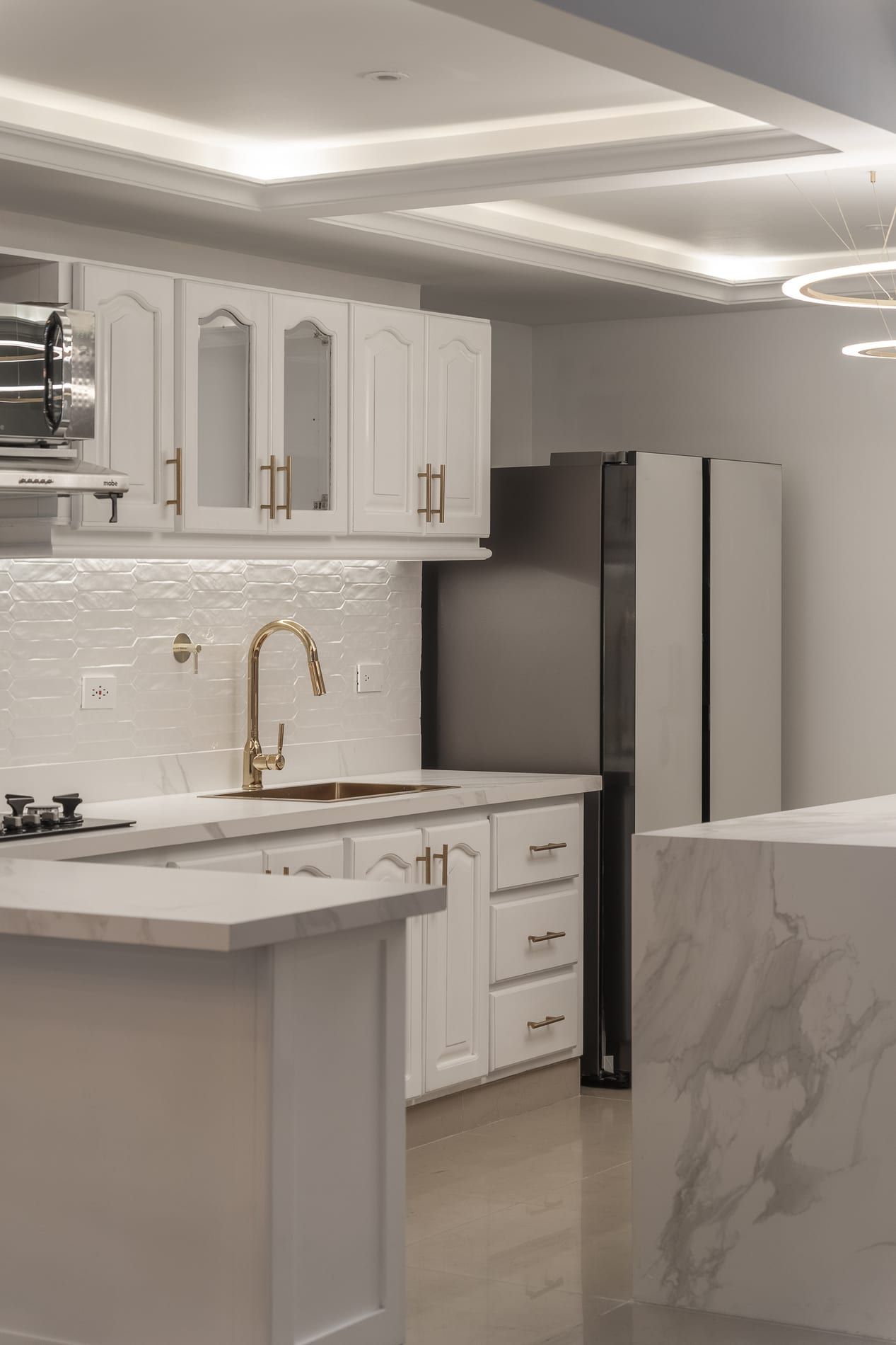 Cocina vista en ángulo, con gabinetes blancos y nevera